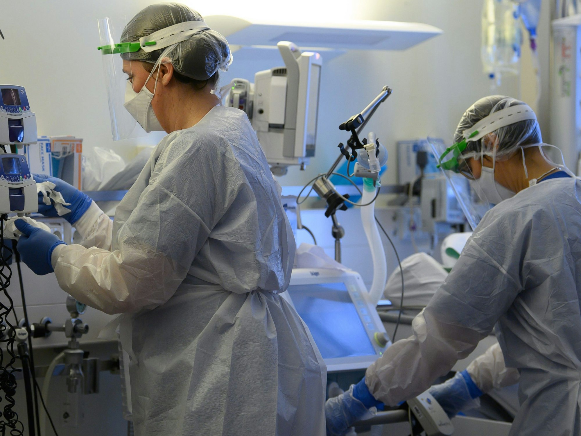 Intensivpflegerinnen sind in Schutzkleidungen auf der Covid-19-Intensivstation einer Klinik mit der Versorgung von Corona-Patienten beschäftigt.