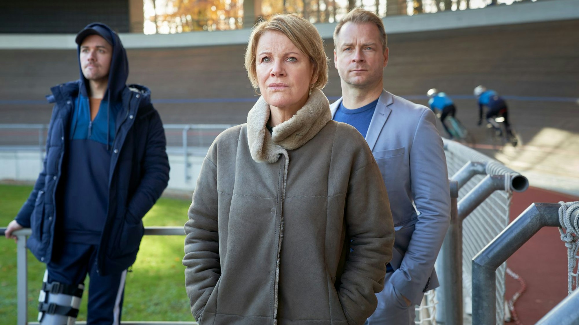 Marie Brand (Mariele Millowitsch, M.), Jürgen Simmel (Hinnerk Schönemann, r.) und Tharde Rickling (Fred Costea, l.) beobachten gespannt das Bahnrad-Training.