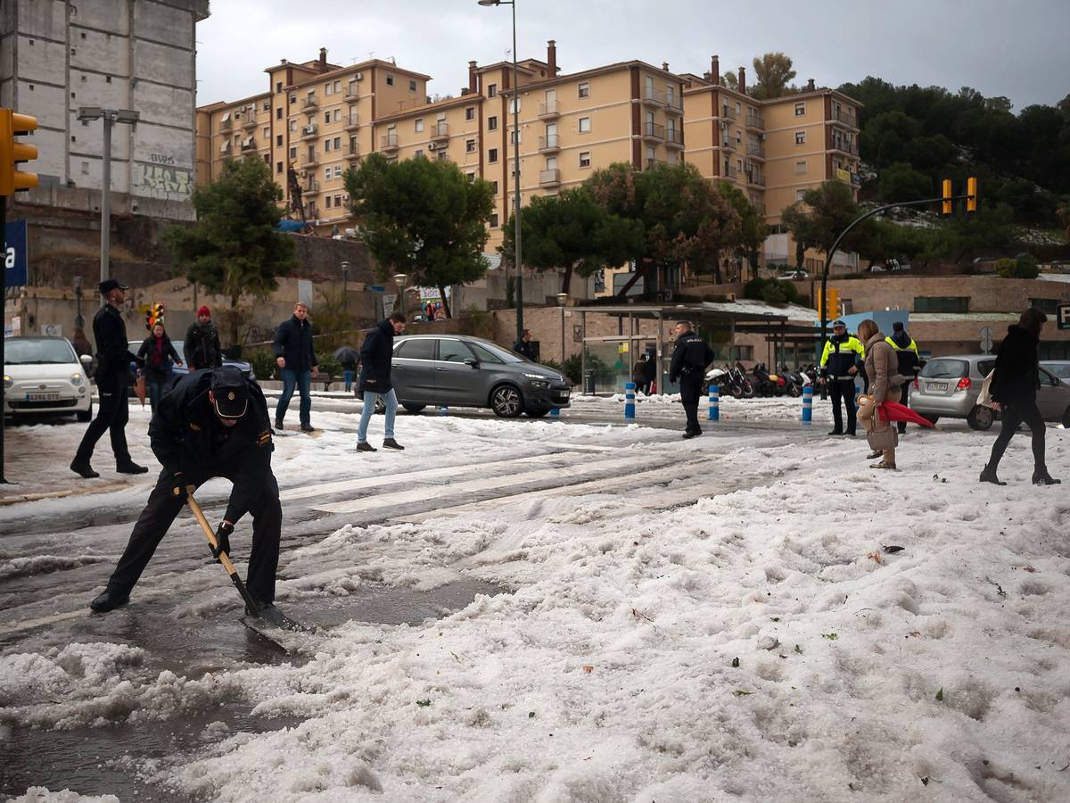 Ein Polizist räumt nach einem schweren Hagelsturm in der Innenstadt von Malaga den Hagel von der Straße. Das Sturmtief «Gloria» hat in Spanien große Schäden hinterlassen.
