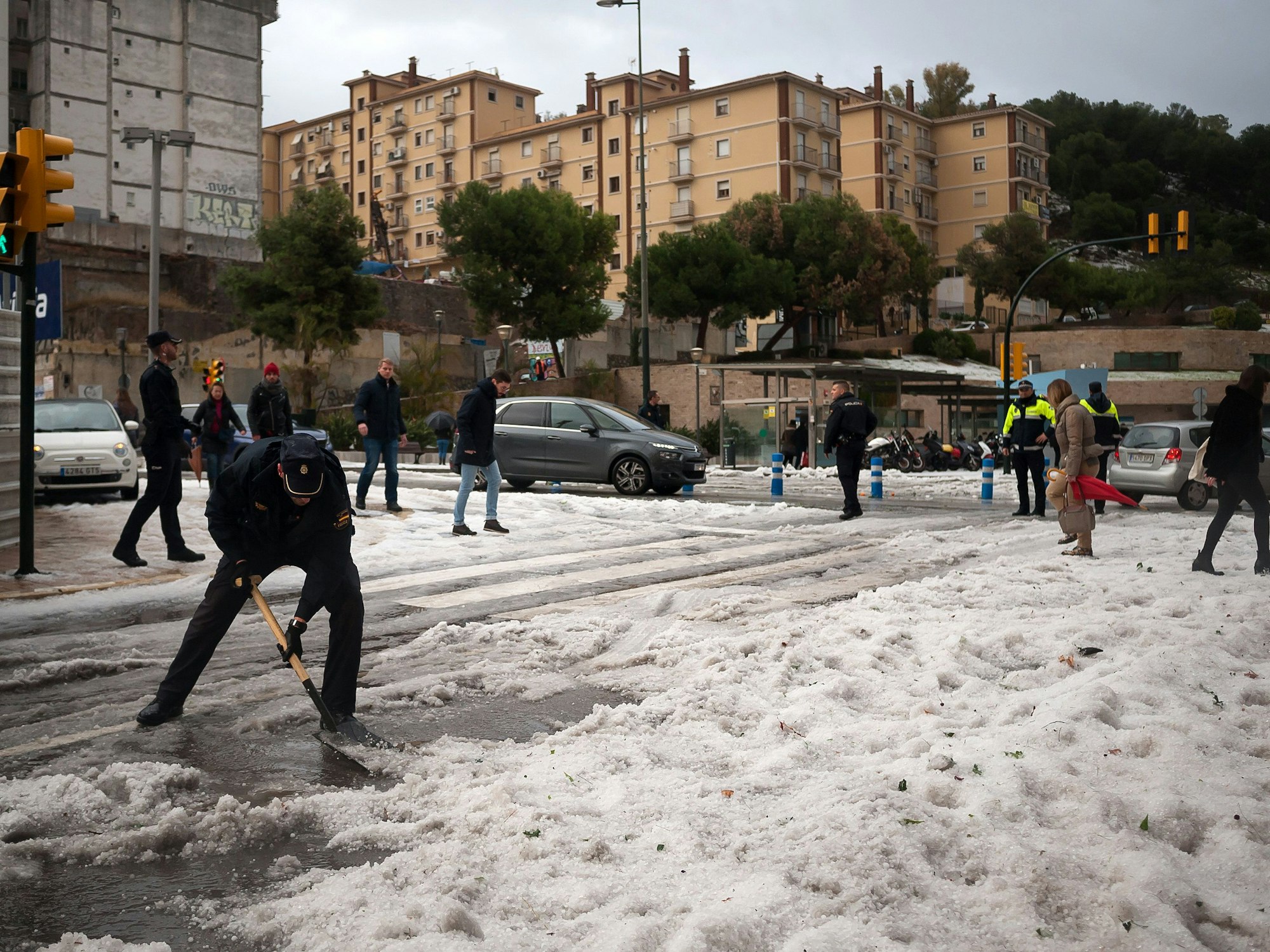 Ein Polizist räumt nach einem schweren Hagelsturm in der Innenstadt von Malaga den Hagel von der Straße. Das Sturmtief «Gloria» hat in Spanien große Schäden hinterlassen.