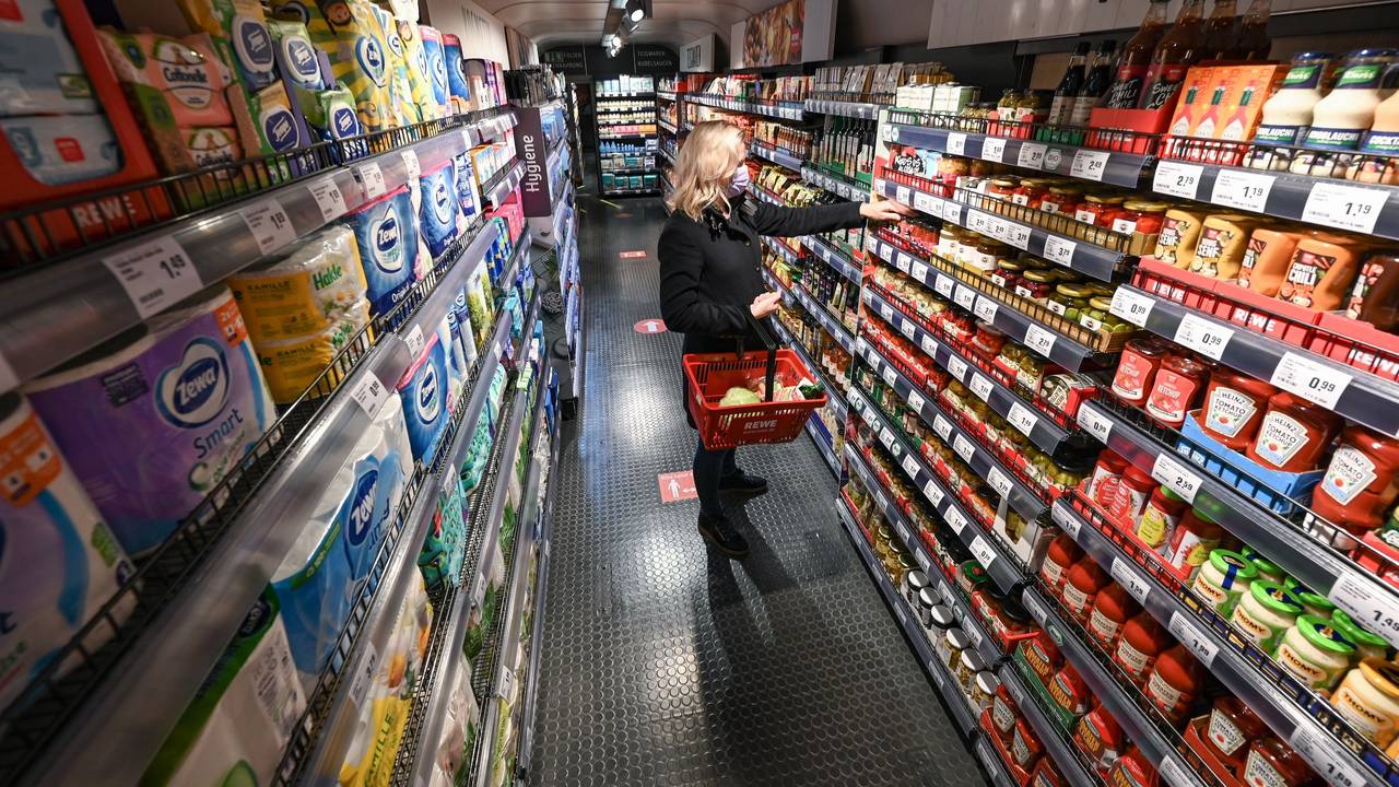 Eine Frau steht bei der Vorstellung des temporären Projekts "Fairer Supermarkt im Zug" im Frankfurter Hauptbahnhof mit einem Einkaufskorb vor einem Lebensmittelregal.