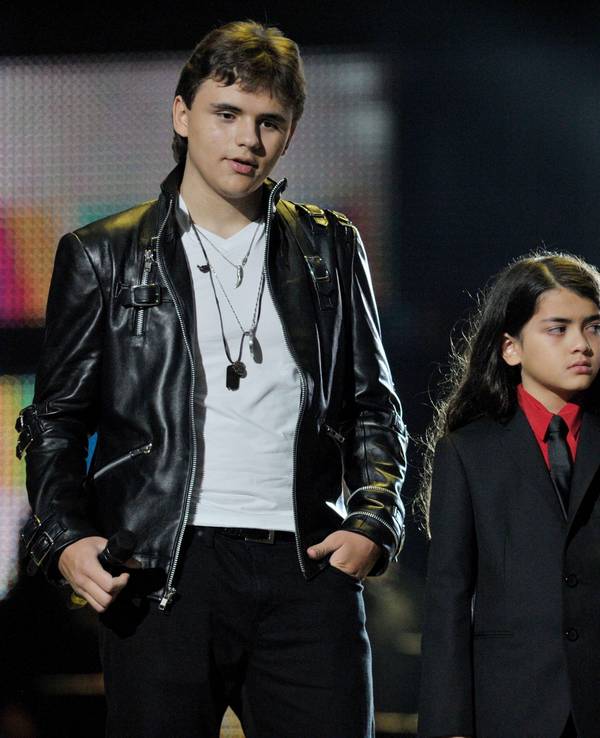 Blanket Jackson steht in einem schwarzen Anzug und einem roten Hemd mit seinen Geschwistern Prince (l.) und Paris (r.) am 08. Oktober 2011 auf einer Bühne.