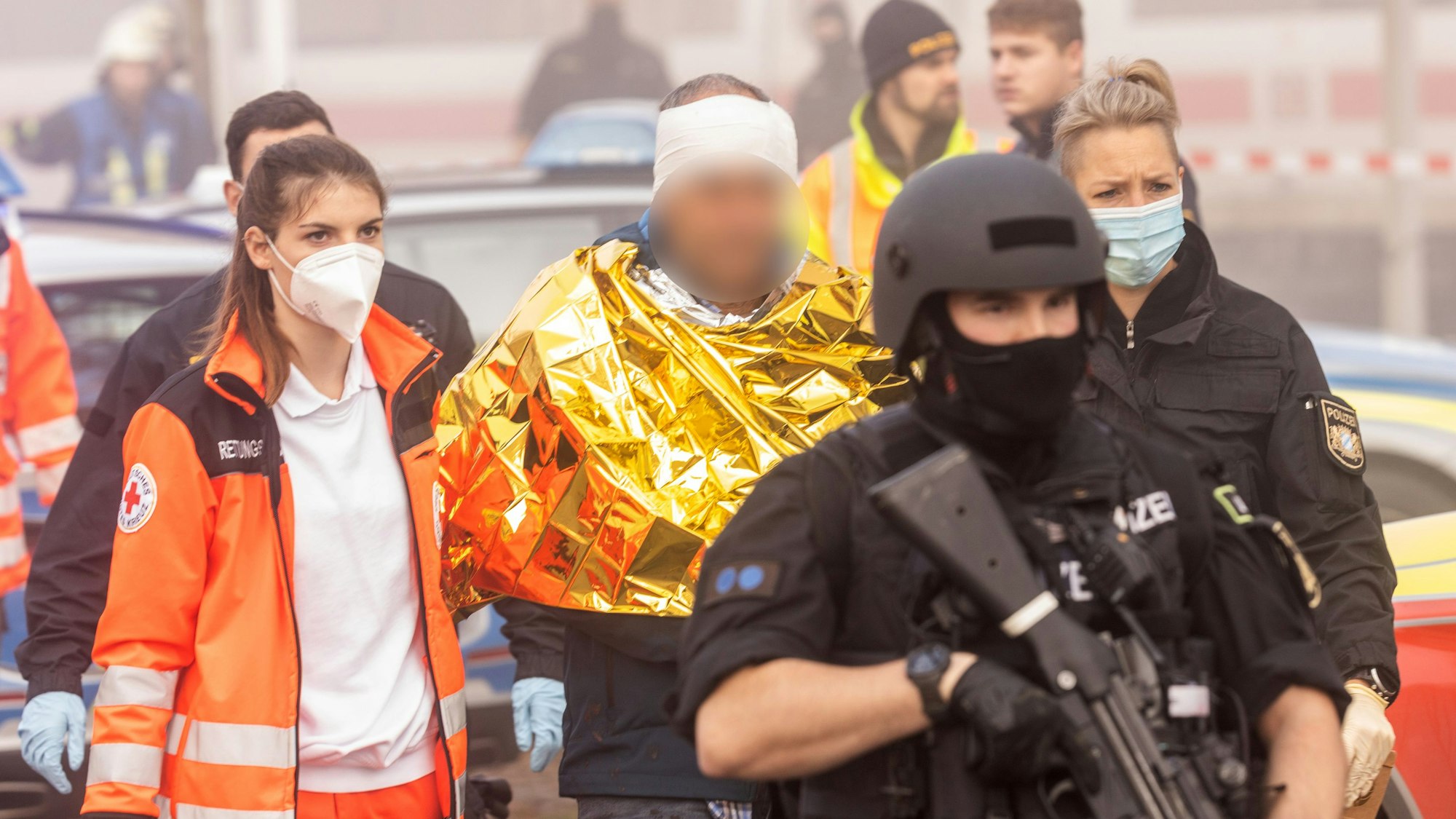 Bayern, Seubersdorf: Eine festgenommene männliche Person wird am Bahnhof von Polizei und Rettungskräften weggeführt.
