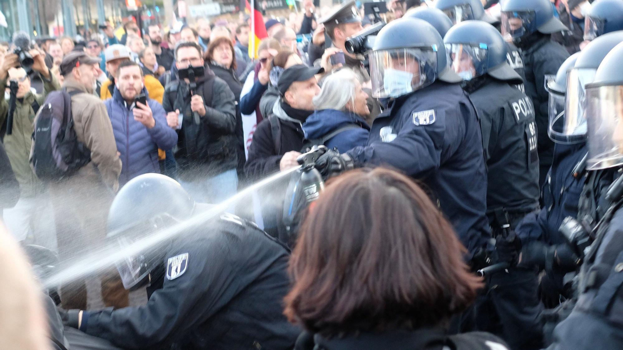 06.11.2021, Sachsen, Leipzig: Ein Polizist setzt Pfefferspray gegen Teilnehmer einer Kundgebung von Kritikern der Coronamaßnahmen der Bundesregierung ein.