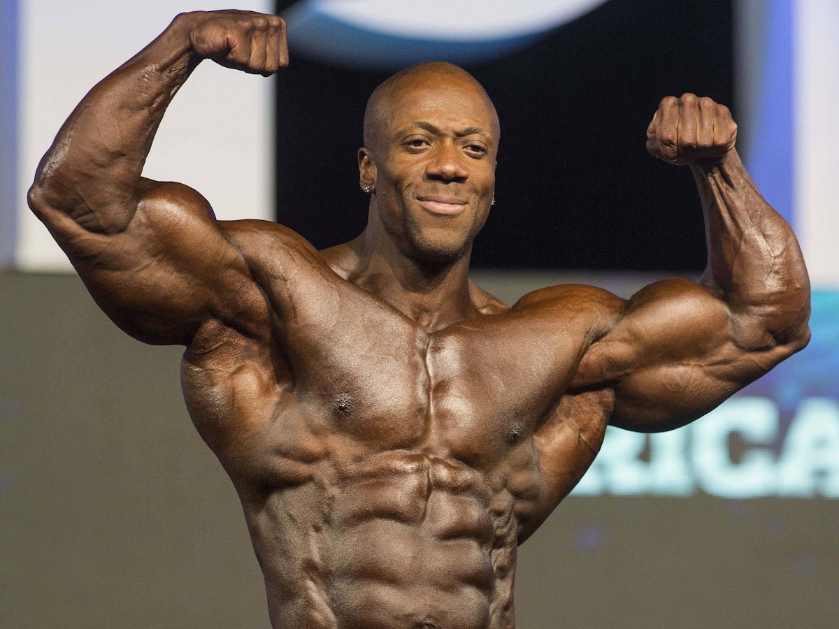 Bodybuilder Shawn Rhoden posiert bei Mr. Olympia mit angespannten Muskeln.