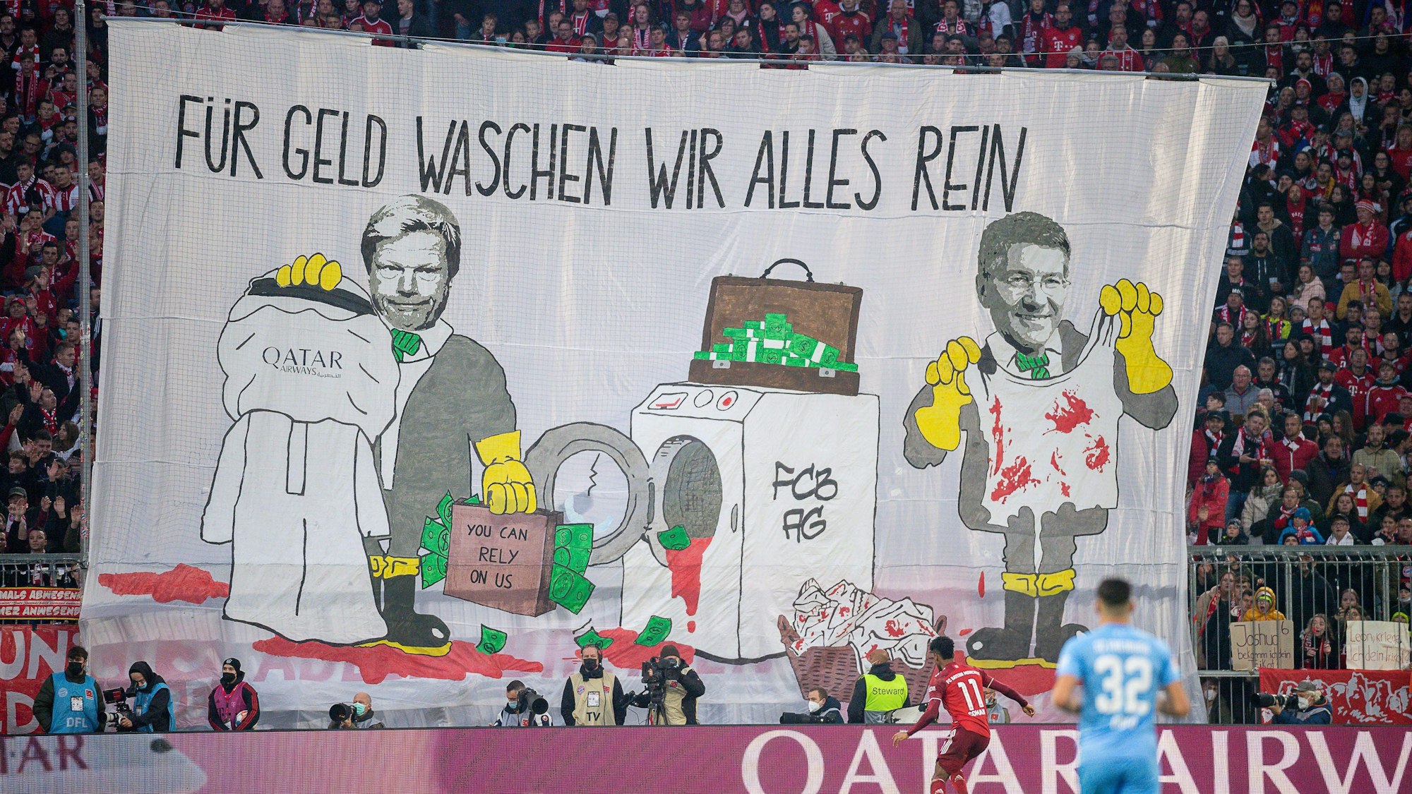 Mit einem Transparent „Für Geld waschen wir alles rein“ protestieren Fans von Bayern München gegen die Geschäftsbeziehungen des Rekordmeisters mit Katar.