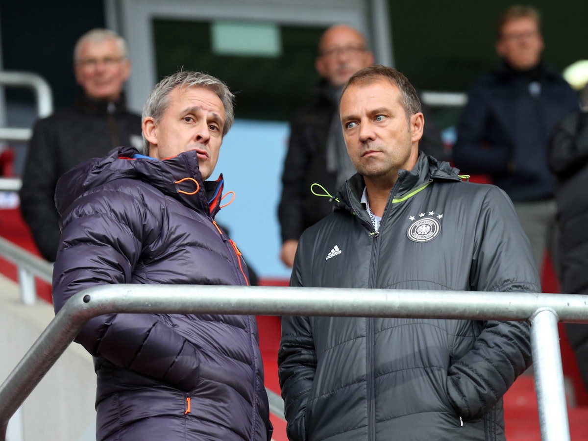 Pierre Littbarski und Hansi Flick stehen gemeinsam auf der Tribüne.