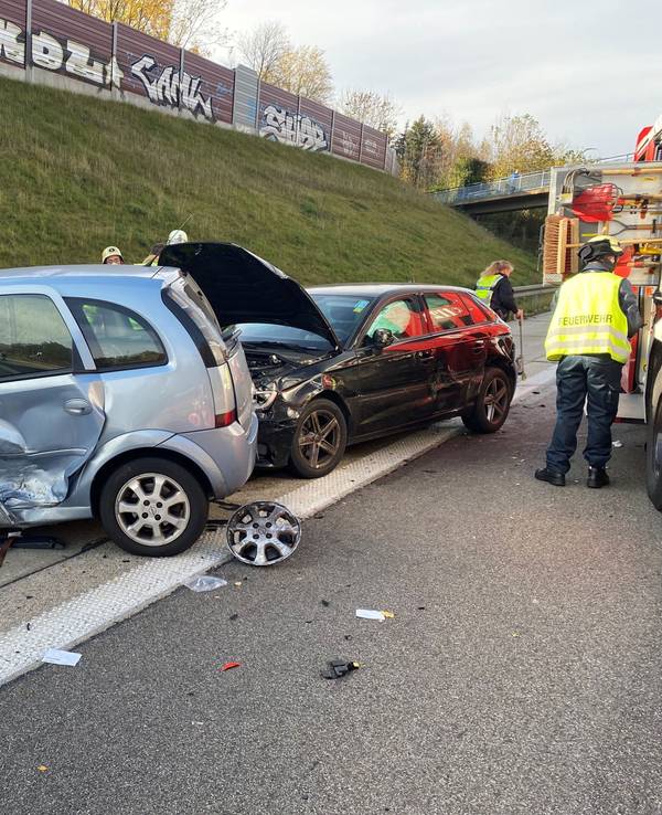 Zwei stark beschädigte Autos stehen auf dem Seitenstreifen einer Autobahn.