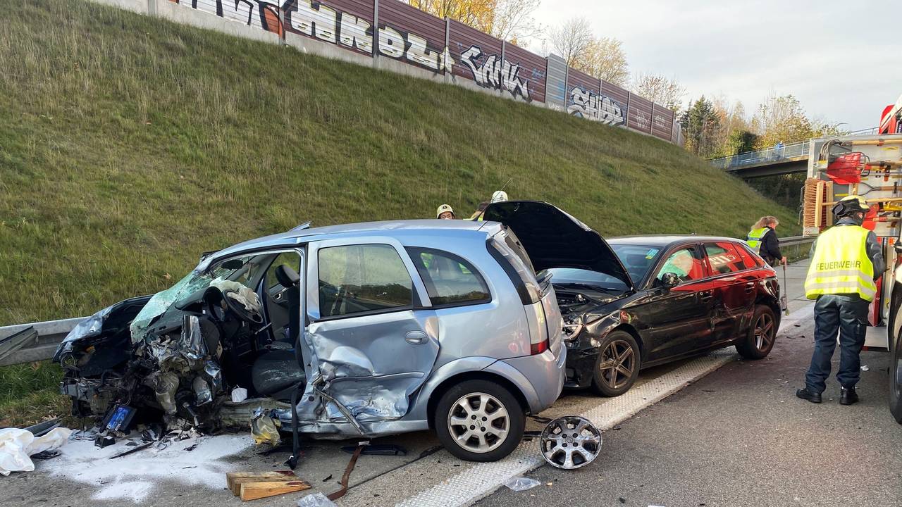 Zwei stark beschädigte Autos stehen auf dem Seitenstreifen einer Autobahn.