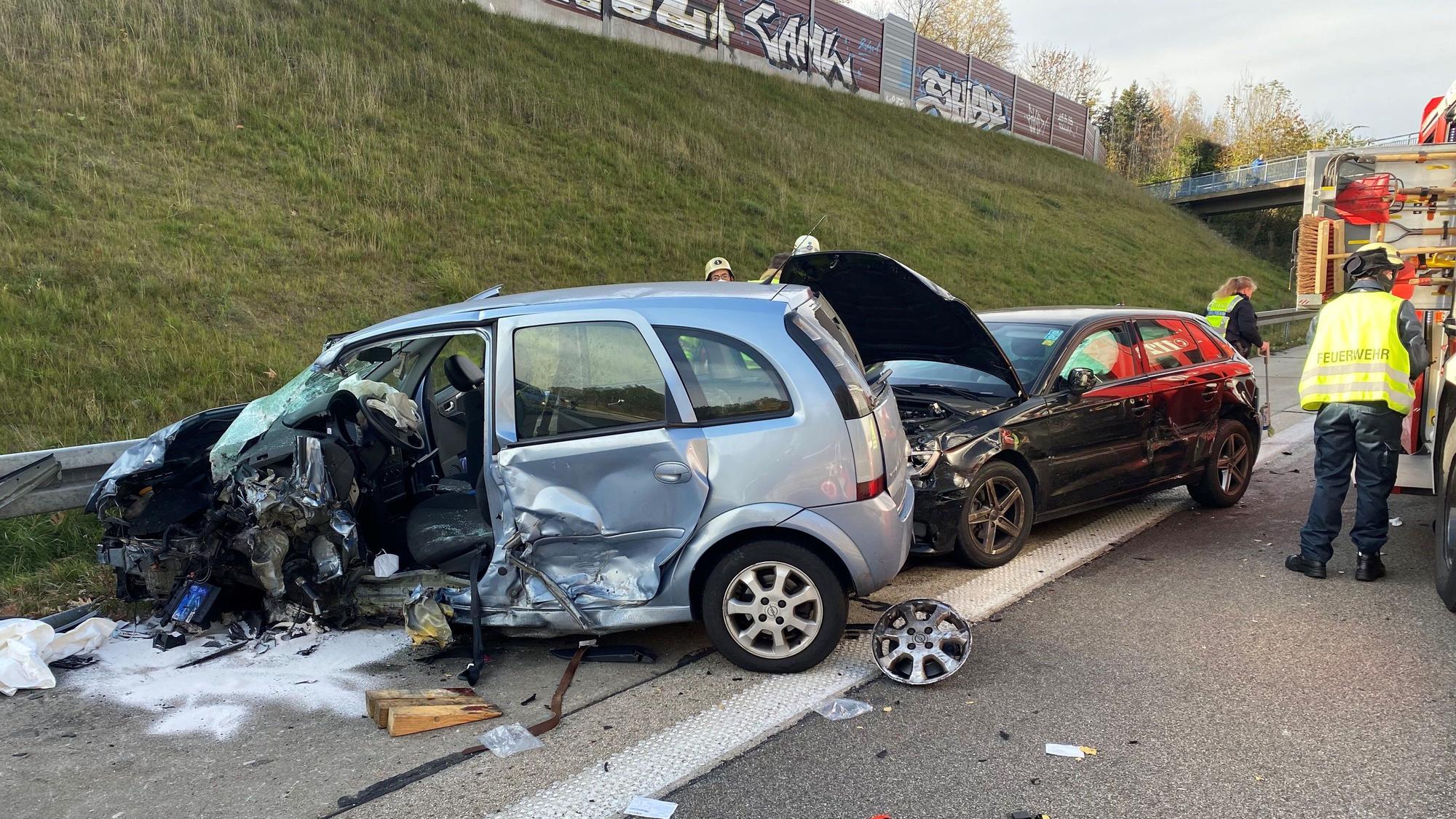 Zwei stark beschädigte Autos stehen auf dem Seitenstreifen einer Autobahn.