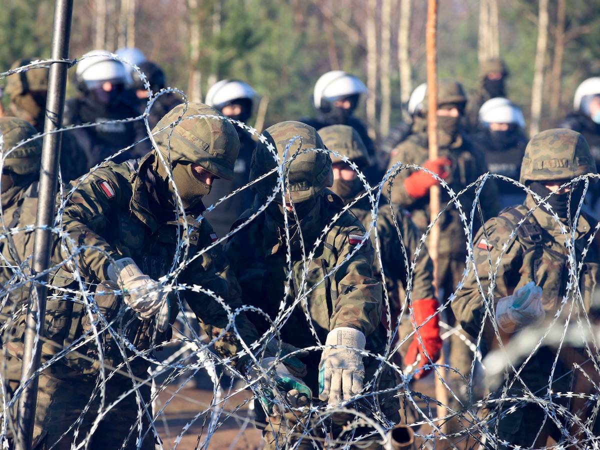 Migranten durchbrechen Grenze von Belarus nach Polen. Auf dem Foto (aufgenommen am 9. November 2021) sind polnische Polizisten und Grenzschützer zu sehen, welche am Stacheldraht stehen.