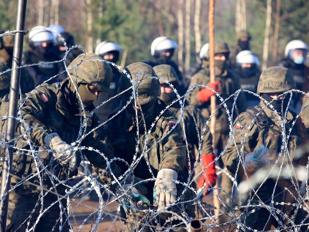 Migranten durchbrechen Grenze von Belarus nach Polen. Auf dem Foto (aufgenommen am 9. November 2021) sind polnische Polizisten und Grenzschützer zu sehen, welche am Stacheldraht stehen.