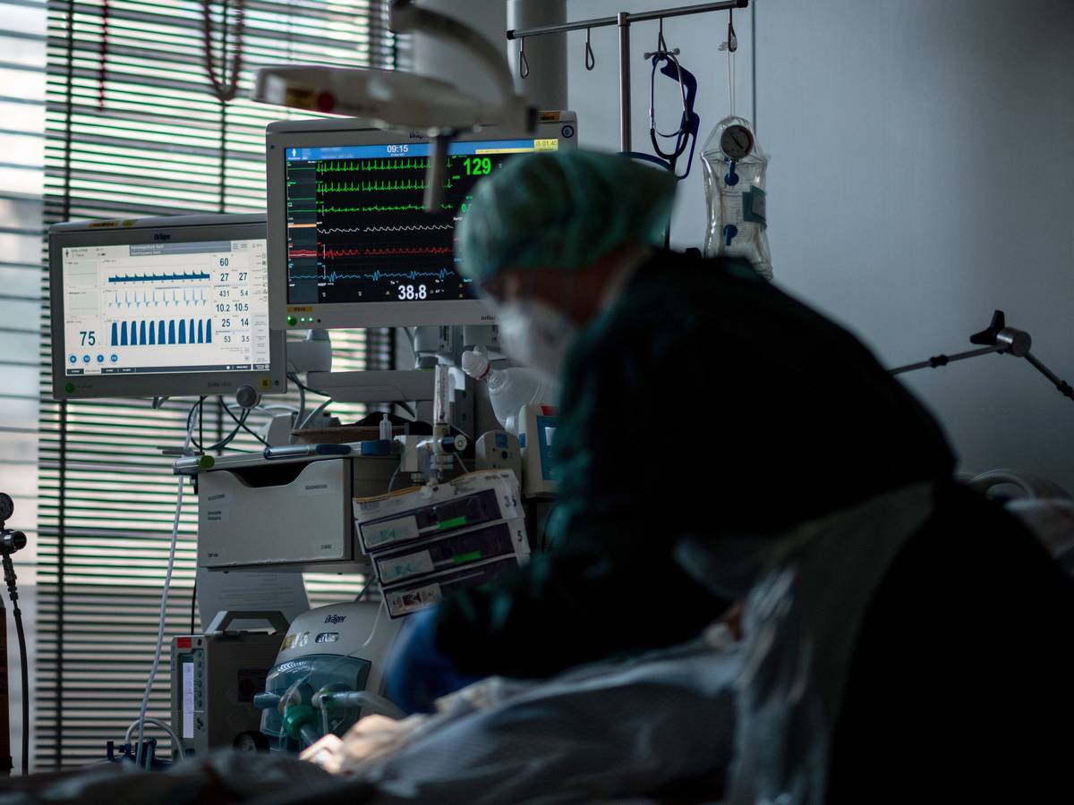 Eine Mitarbeiterin der Pflege steht in einem Zimmer auf der Corona-Intensivstation des Universitätsklinikums Essen und behandelt einen Patienten.