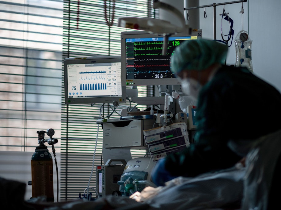 Eine Mitarbeiterin der Pflege steht in einem Zimmer auf der Corona-Intensivstation des Universitätsklinikums Essen und behandelt einen Patienten.