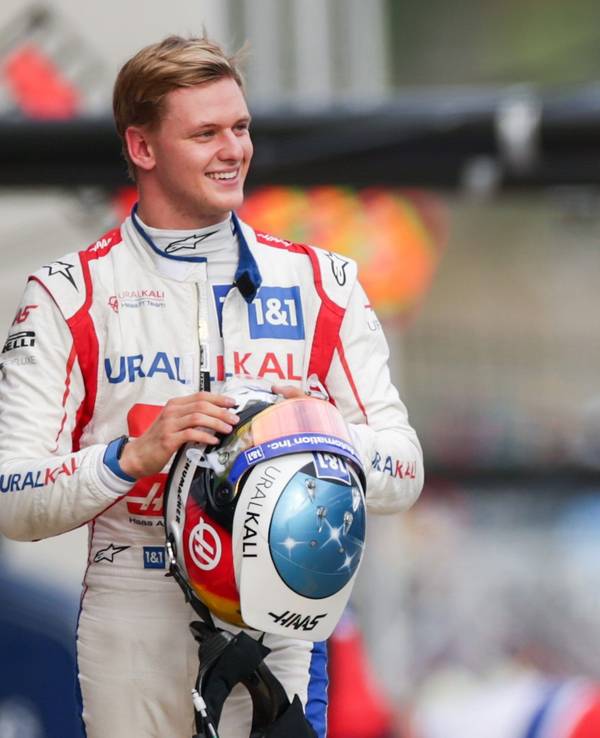 Mick Schumacher geht lachend durch die Boxengasse der Formel 1.