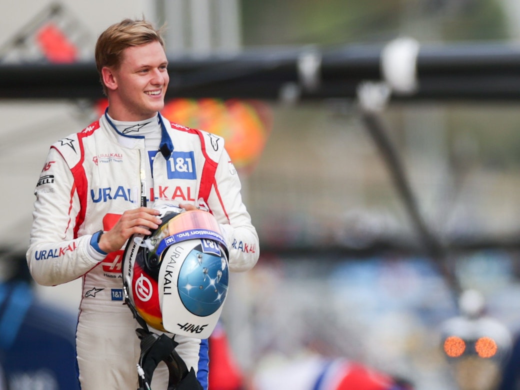 Mick Schumacher geht lachend durch die Boxengasse der Formel 1.