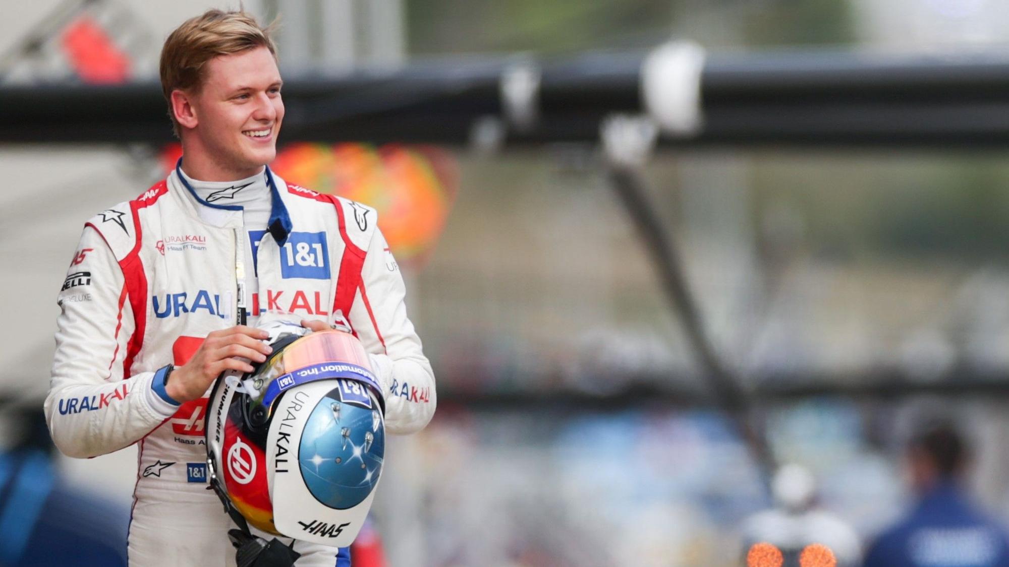 Mick Schumacher geht lachend durch die Boxengasse der Formel 1.