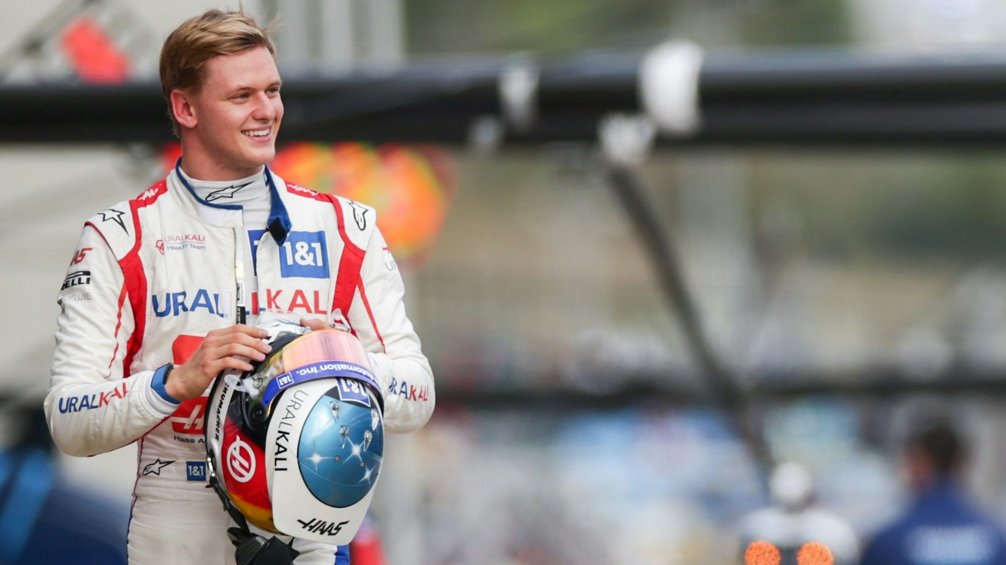 Mick Schumacher geht lachend durch die Boxengasse der Formel 1.