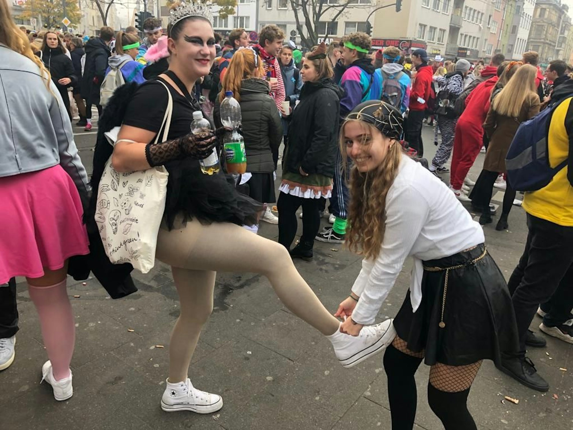 Sophia (20) bindet ihrer Freundin Kira (20) den Turnschuh zu.