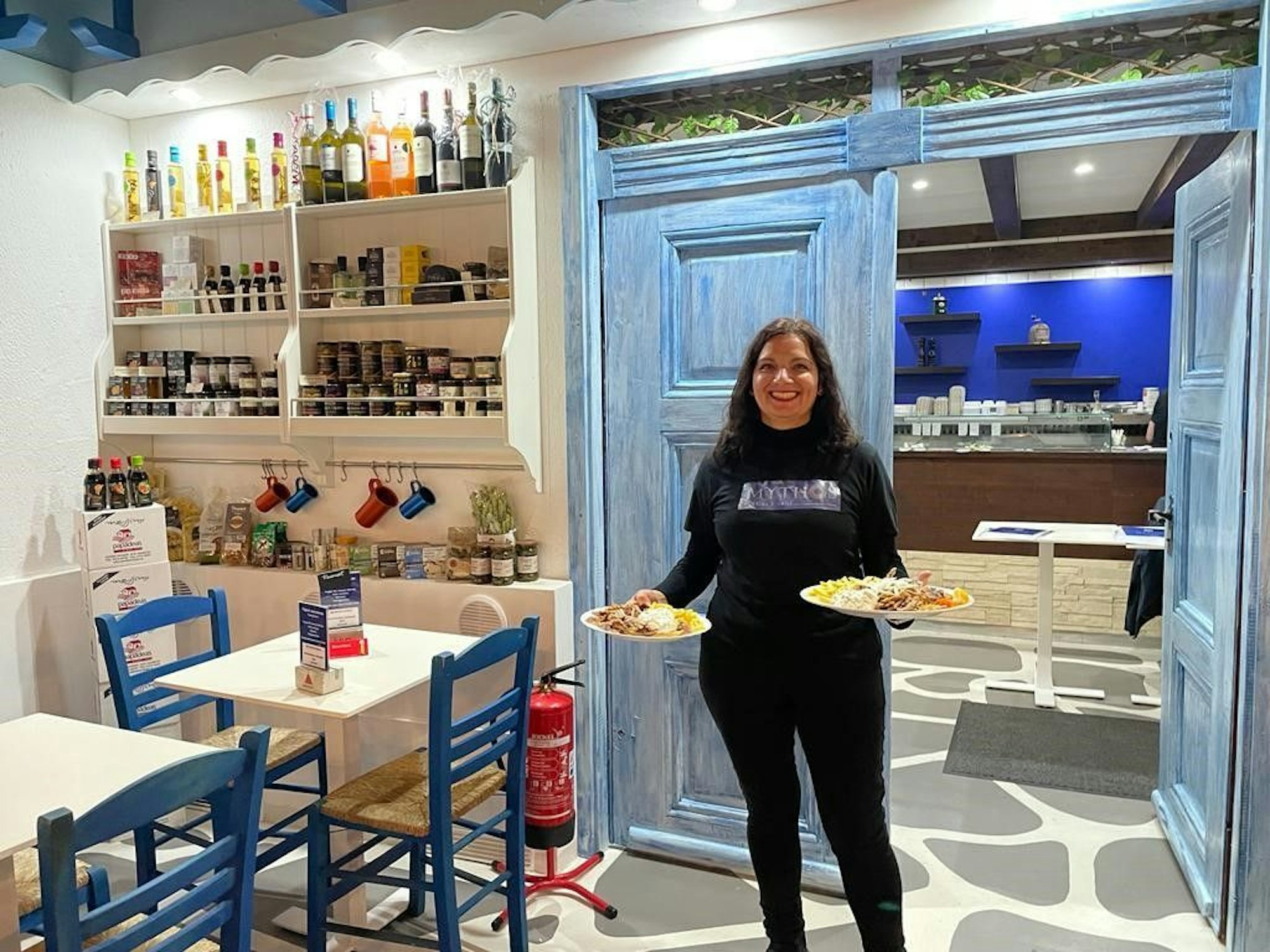 Die Wirtin kommt mit zwei Gerichten auf den Tellern in das Restaurant.