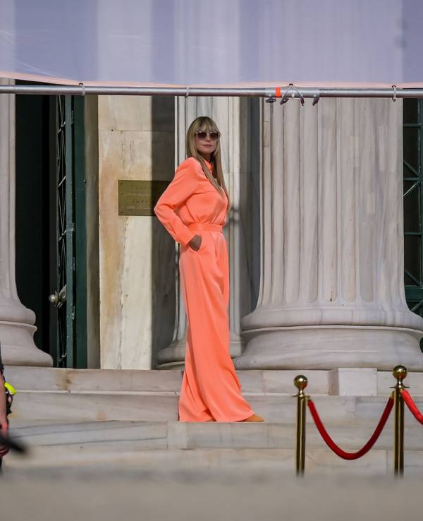 Heidi Klum posiert auf einem Foto vom 05. November 2021 in einem orange-farbigen Kleid am Eingang der Zappeion-Halle während der Dreharbeiten für „Germany's Next Topmodel“.