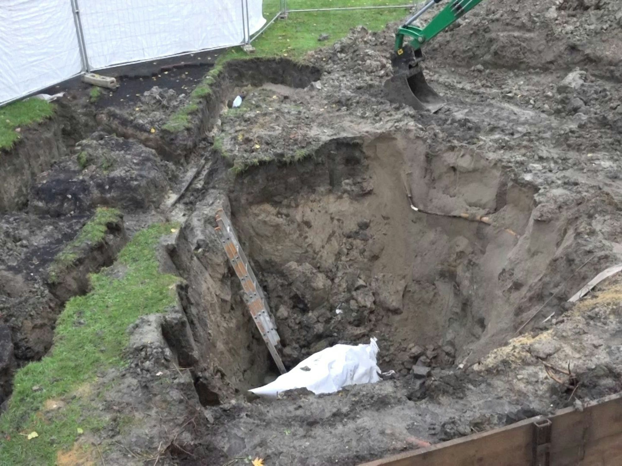 Mit einer Plane abgedeckt liegt eine Luftmine in einer Baugrube.