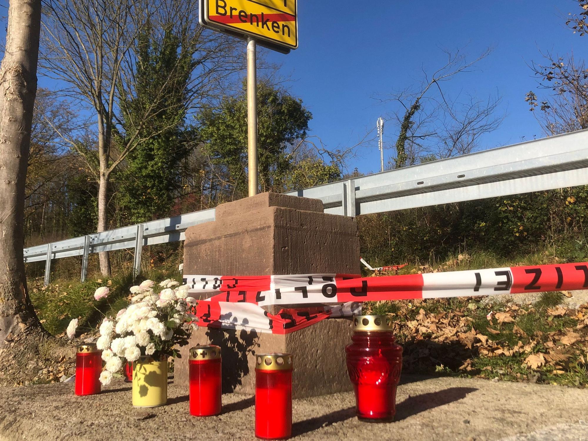 Absperrband der Polizei und Kerzen am Sockel eines Sandstein-Kreuzes in Büren-Breken, das am 11. November 2021 einen Jungen erschlagen hat.