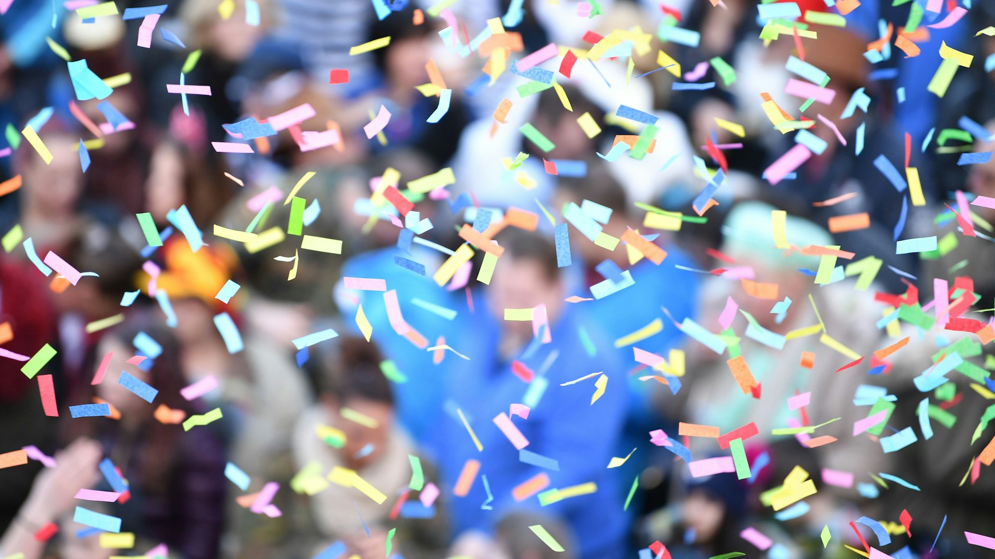 Jecke stehen unter einem Konfettiregen.