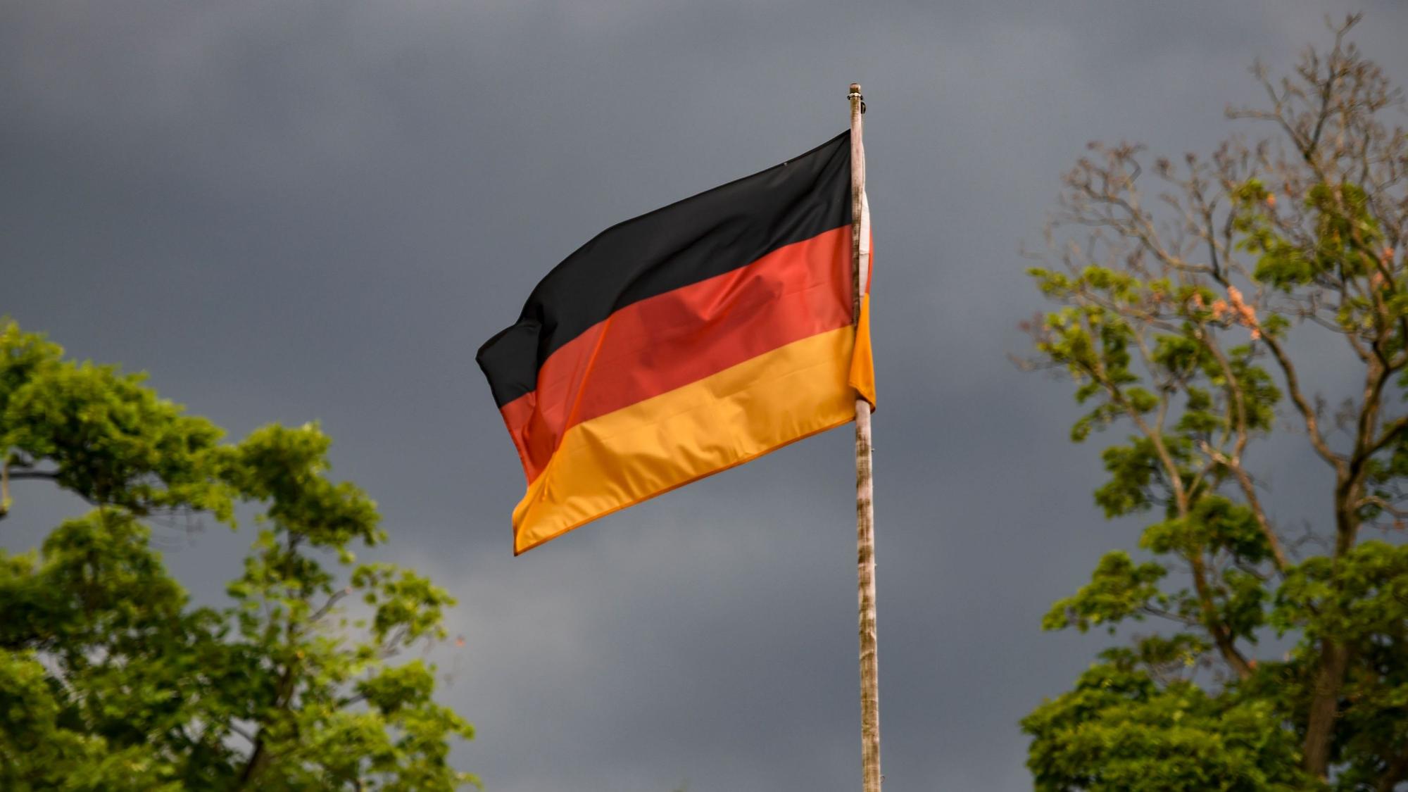 Die deutsche Flagge weht vor dunklen Wolken im Wind. Heute ist das Spiel der deutschen Mannschaft gegen England im Achtelfinale. +++ dpa-Bildfunk +++
