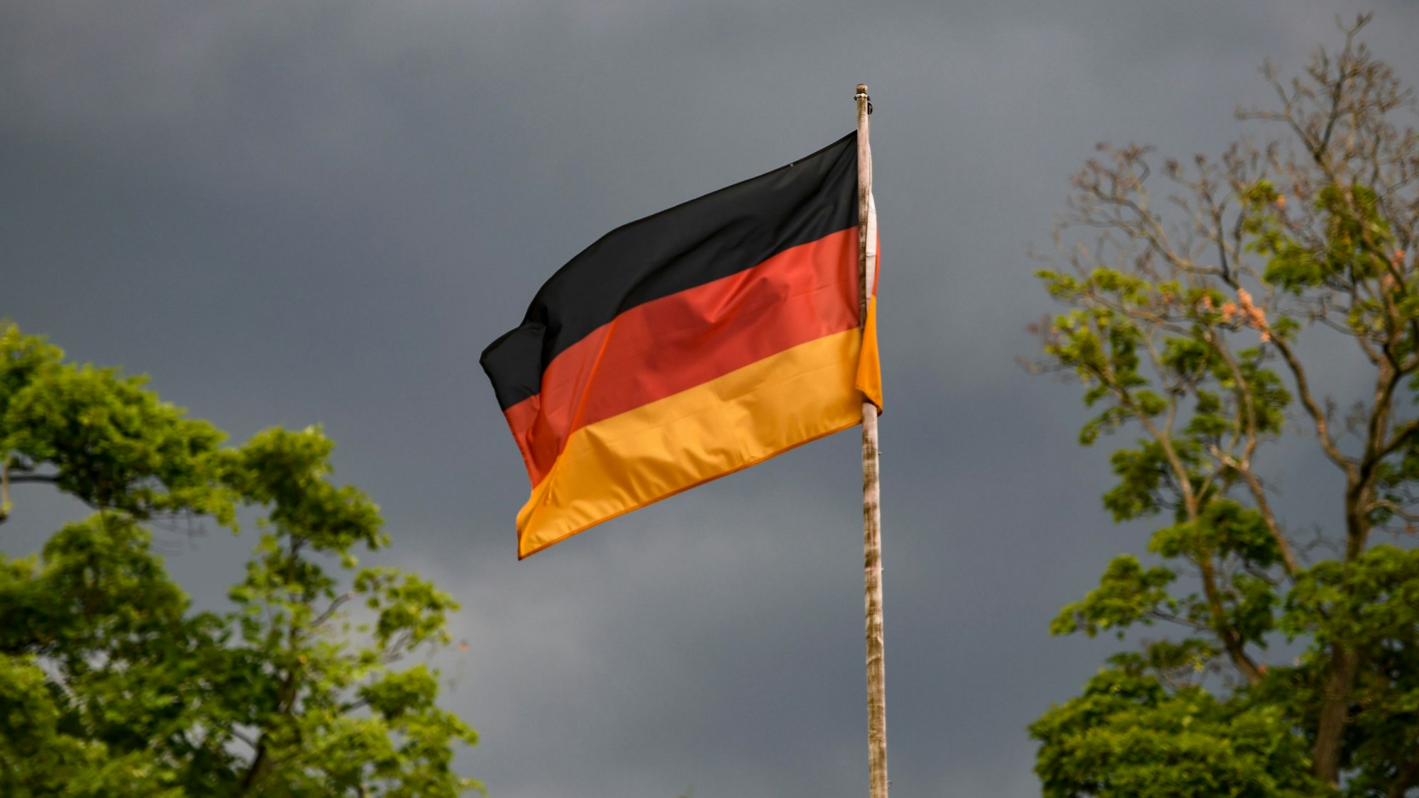 Die deutsche Flagge weht vor dunklen Wolken im Wind. Heute ist das Spiel der deutschen Mannschaft gegen England im Achtelfinale. +++ dpa-Bildfunk +++