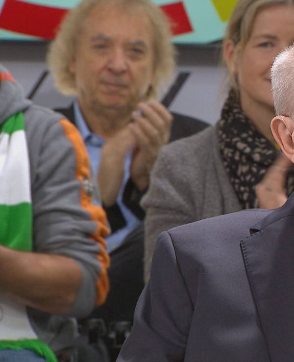 Reiner Calmund sitzt auf einem Stuhl, im Hintergrund sitzen Zuschauer.