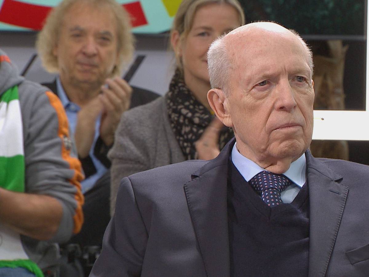 Reiner Calmund sitzt auf einem Stuhl, im Hintergrund sitzen Zuschauer.