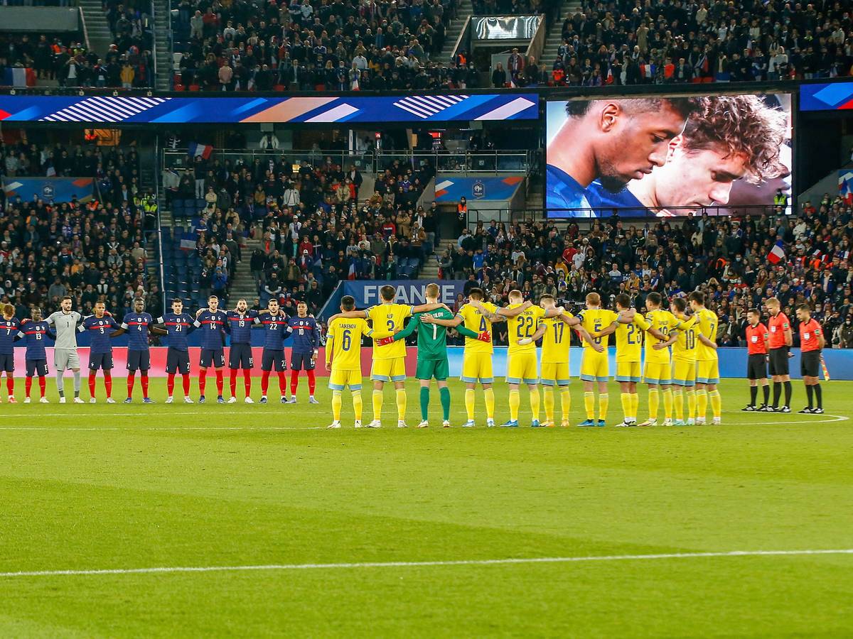Die französischen und kasachischen Spieler stehen Arm in Arm am Mittelkreis.