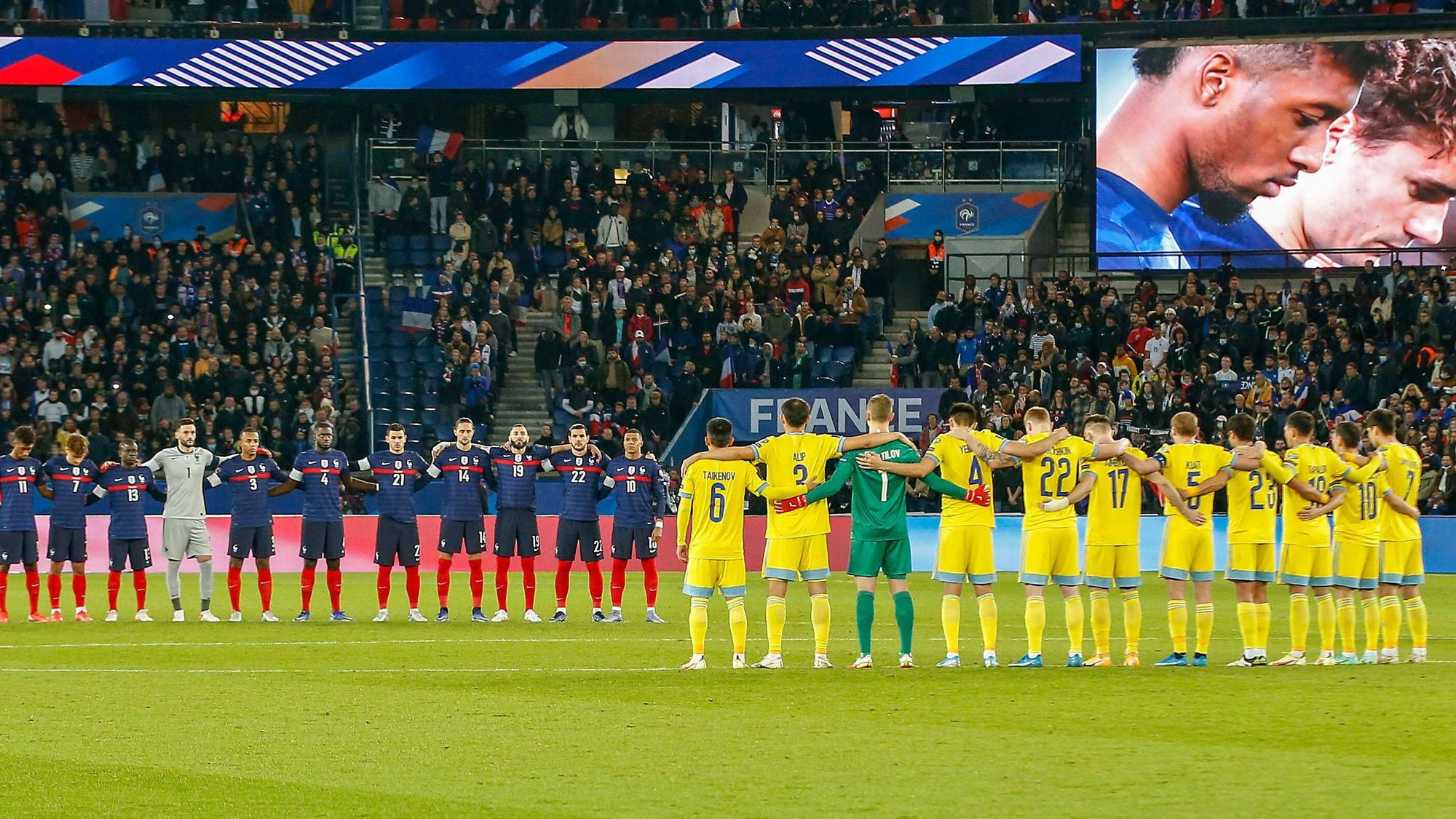 Die französischen und kasachischen Spieler stehen Arm in Arm am Mittelkreis.