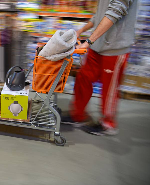 Ein Kunde schiebt in einem Hornbach Baumarkt einen beladenen Einkaufswagen durch einen Gang.