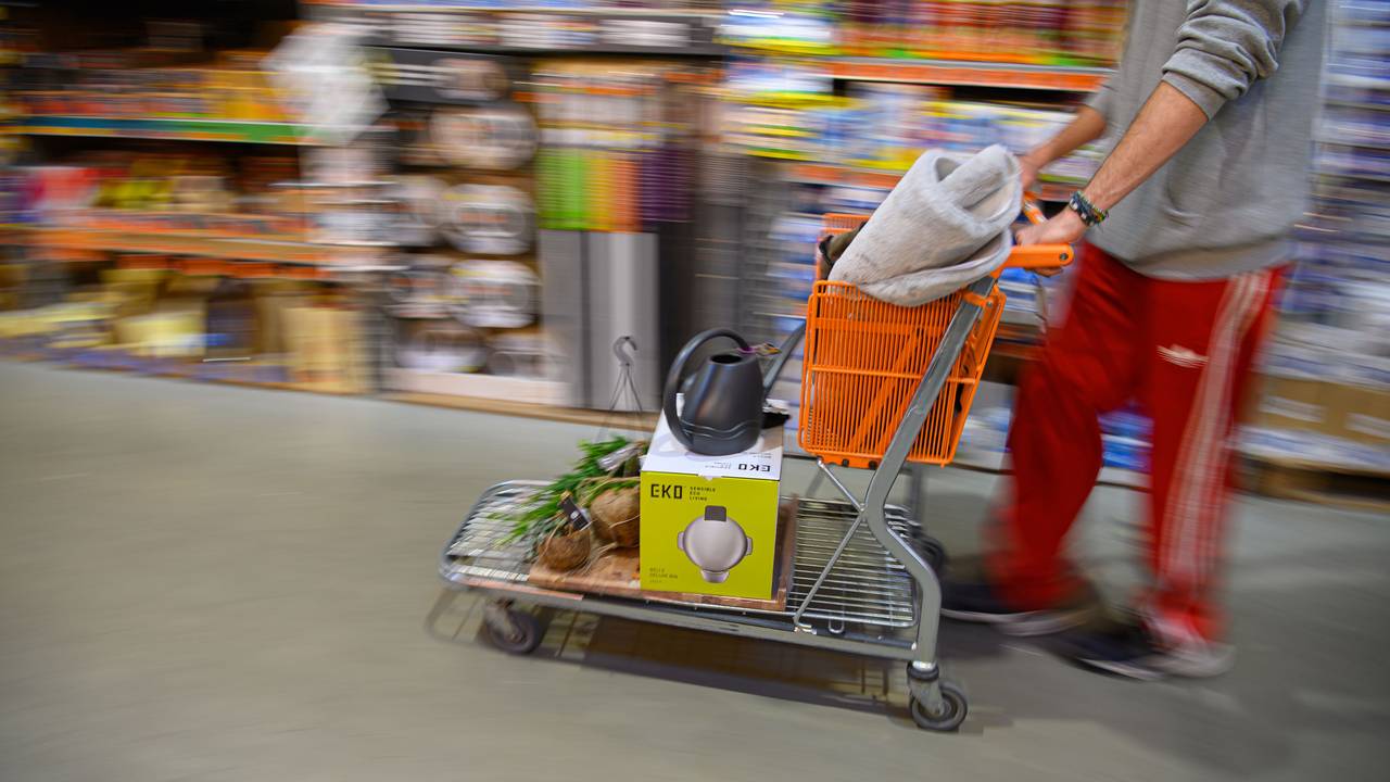 Ein Kunde schiebt in einem Hornbach Baumarkt einen beladenen Einkaufswagen durch einen Gang.