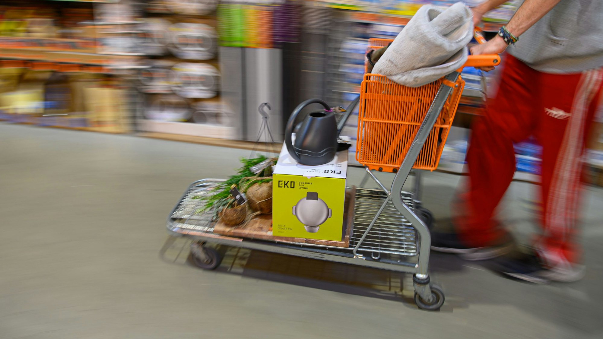 Ein Kunde schiebt in einem Hornbach Baumarkt einen beladenen Einkaufswagen durch einen Gang.