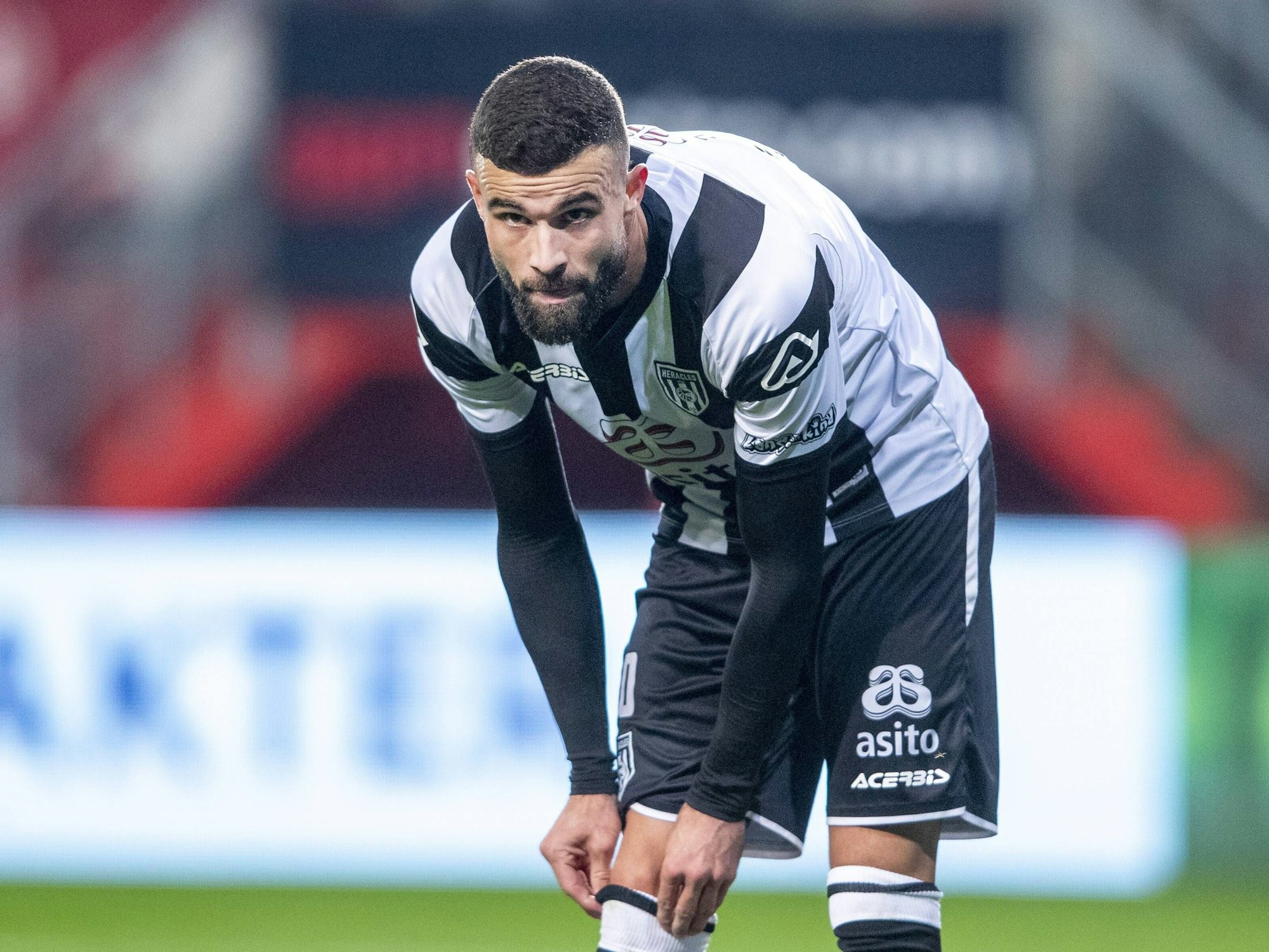 Rai Vloet zieht sich in der Partie Twente Enschede gegen Heracles Almelo die Stutzen hoch und guckt in die Kamera
