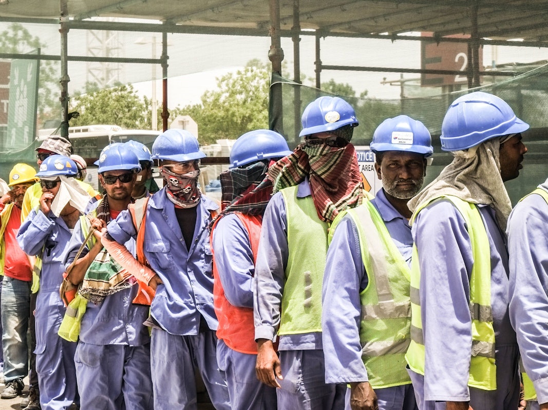 Männer in Arbeitsmontur stehen in einer Schlange.
