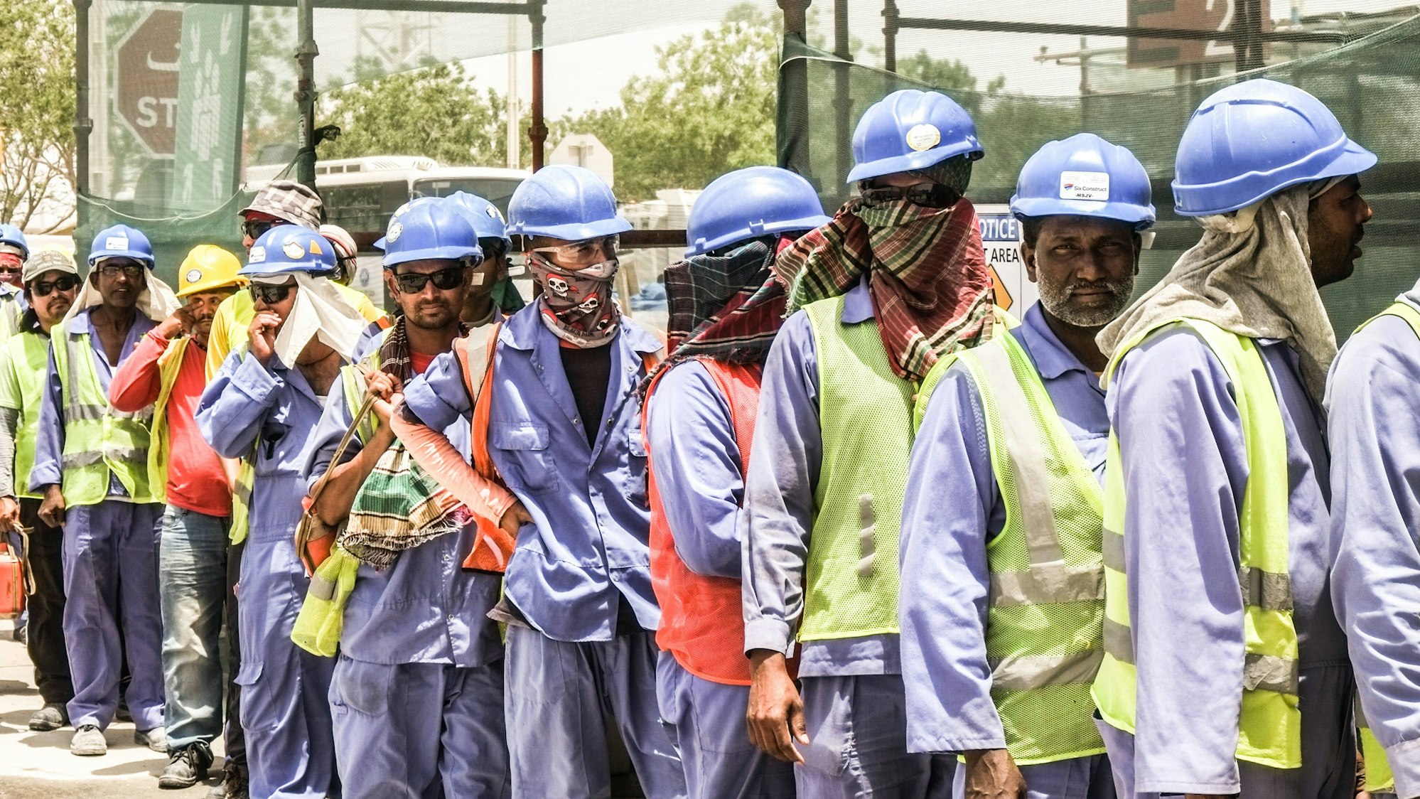 Männer in Arbeitsmontur stehen in einer Schlange.