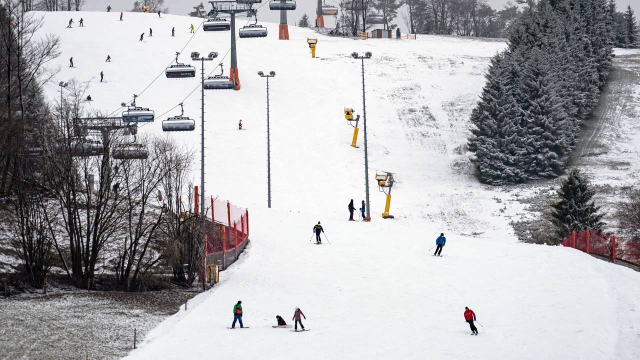Wintersportler und -sportlerinnen auf Skiern und Snowboards fahren am Ettelsberg im Sauerland eine Abfahrt hinunter.