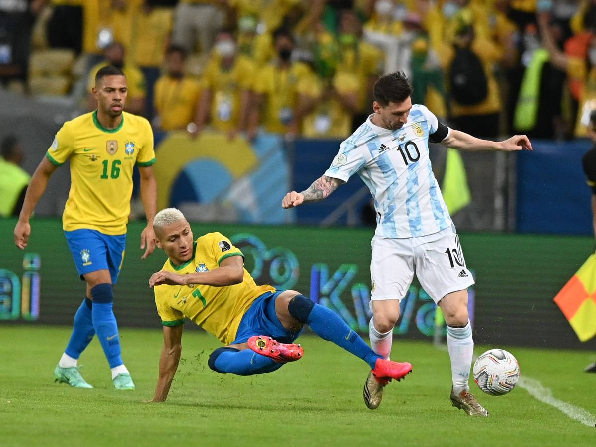 Richarlison aus Brasilien versucht Lionel Messi aus Argentinien zu stoppen, während Renan Lodi zuschaut.
