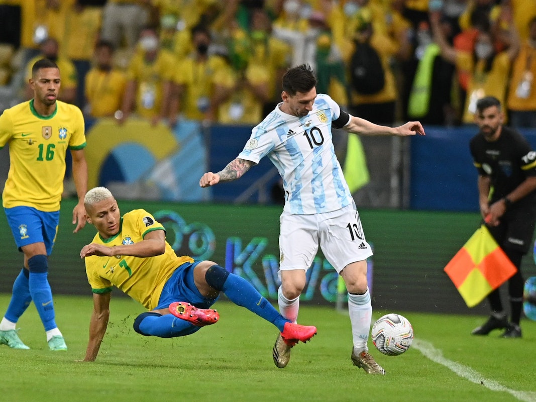 Richarlison aus Brasilien versucht Lionel Messi aus Argentinien zu stoppen, während Renan Lodi zuschaut.