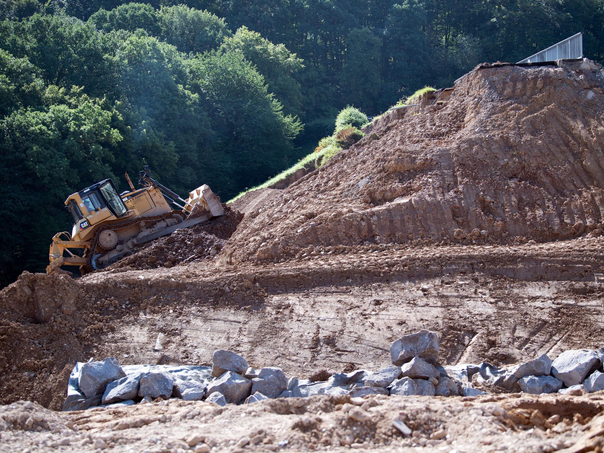 Eine Planierraupe arbeitet an dem vom Hochwasser beschädigten Damm der Steinbachtalsperre.