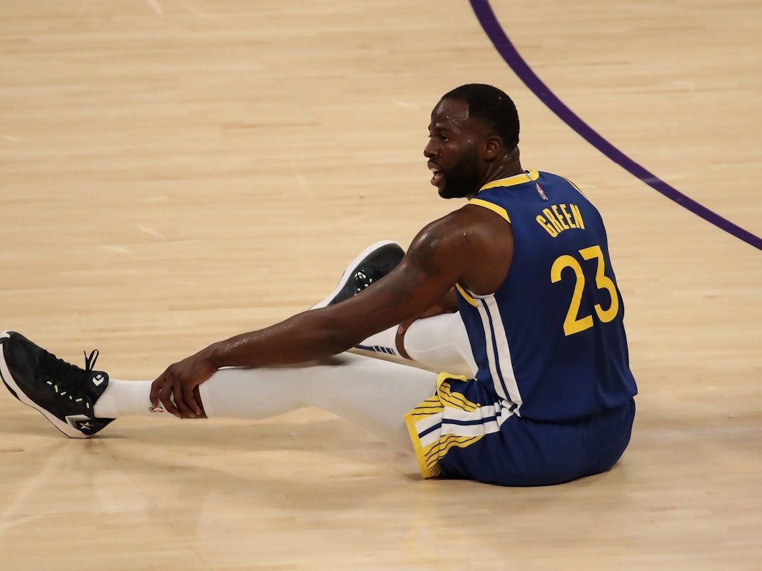 Draymond Green sitzt auf dem Boden des Spielfelds.