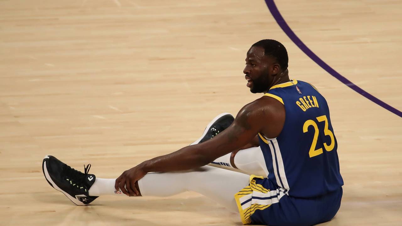 Draymond Green sitzt auf dem Boden des Spielfelds.
