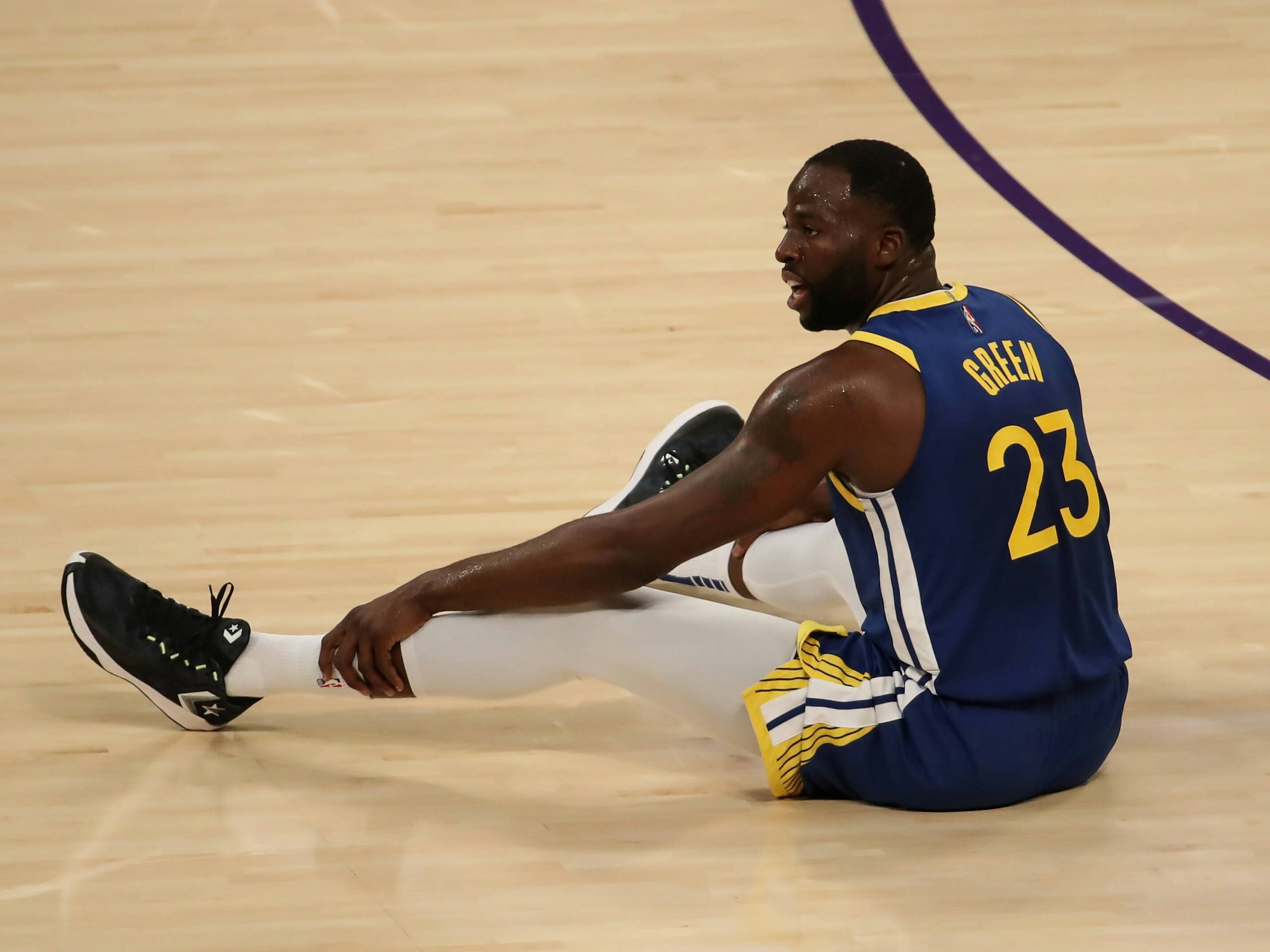 Draymond Green sitzt auf dem Boden des Spielfelds.