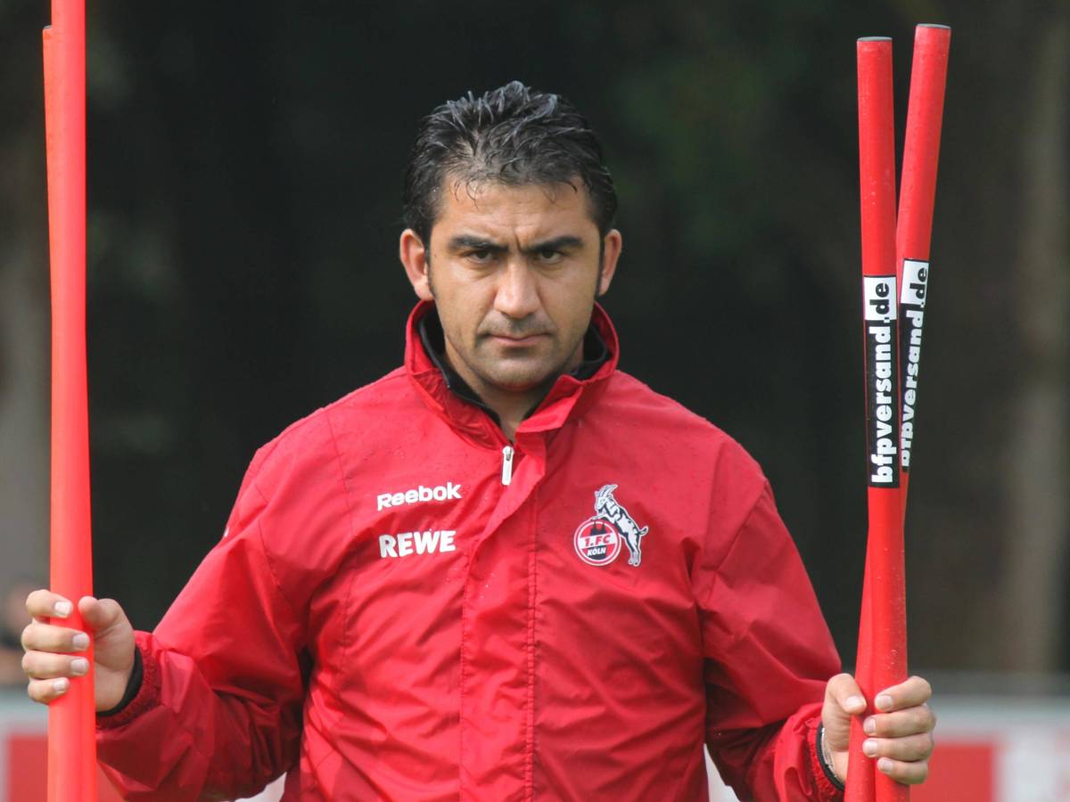 Ümit Özat trägt Stangen beim Training über den Platz.