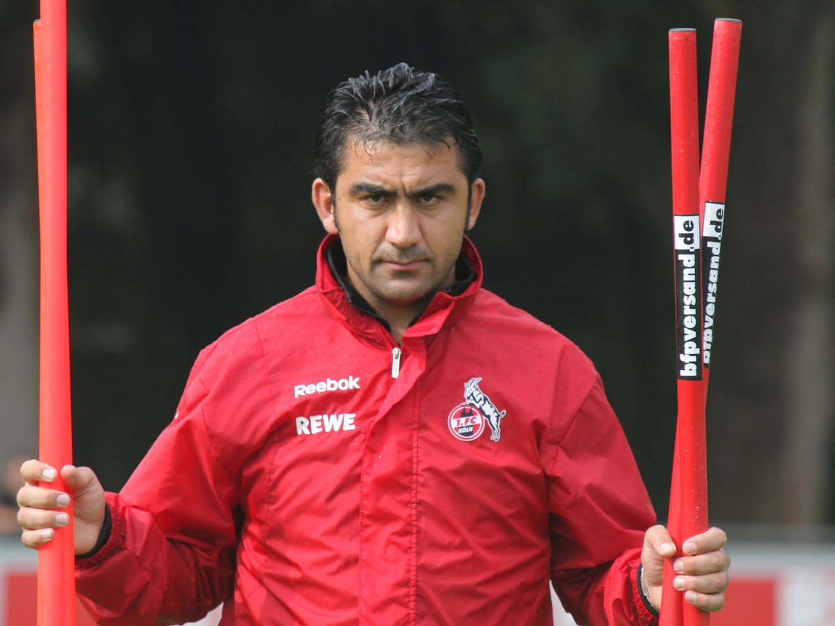 Ümit Özat trägt Stangen beim Training über den Platz.