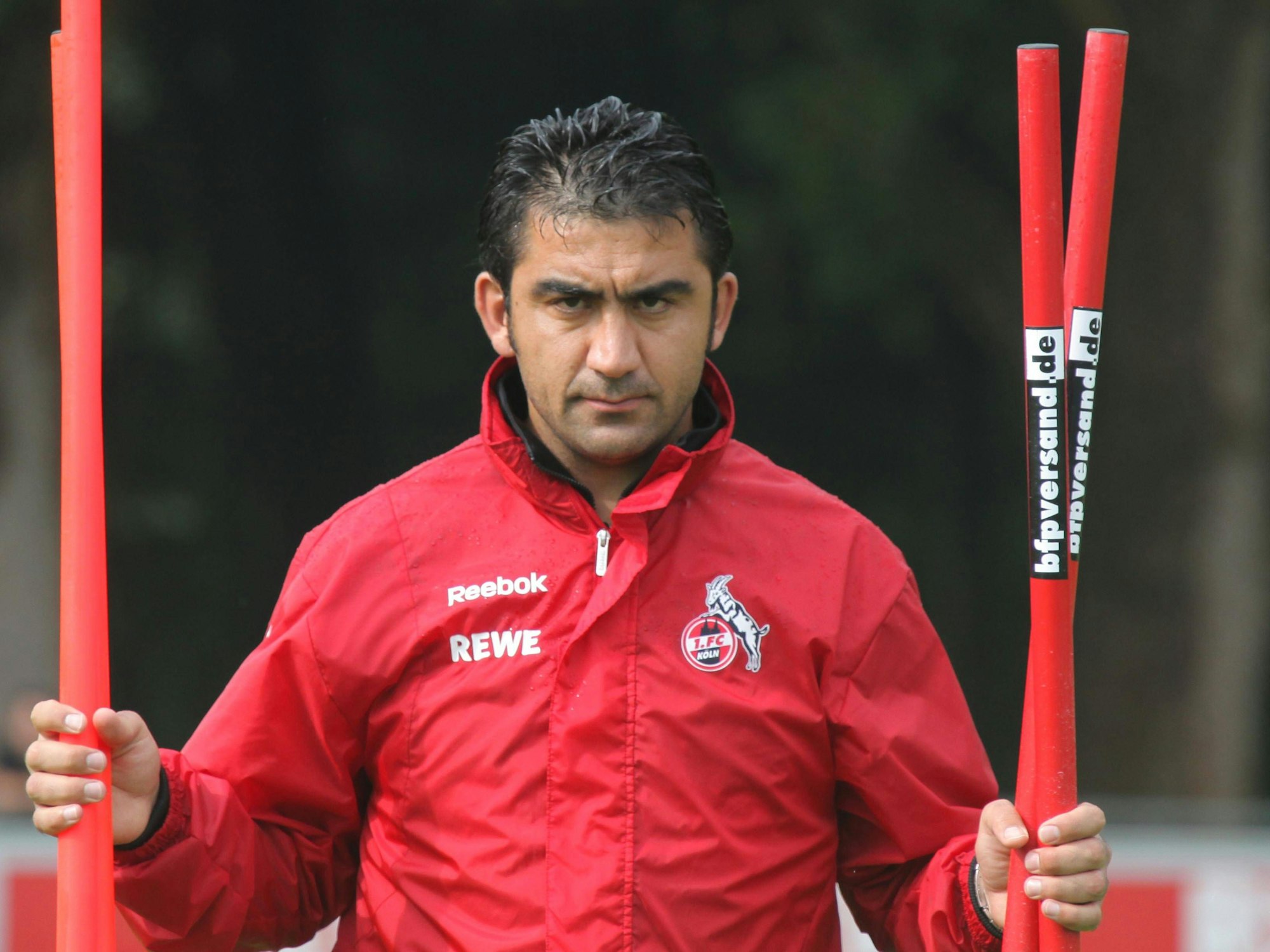 Ümit Özat trägt Stangen beim Training über den Platz.